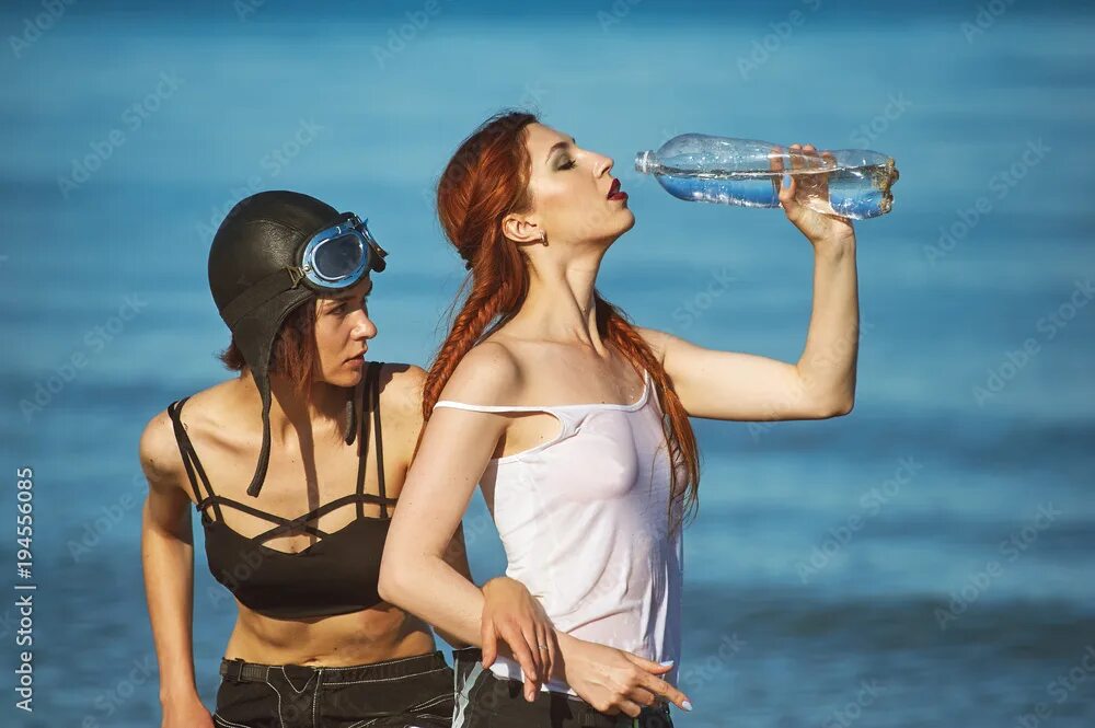 Hot drinking chicks. Две девочки пили воду. Баба пьет на пляже. Девушка с бутылкой на пляже. Девушка пьет воду на пляже.
