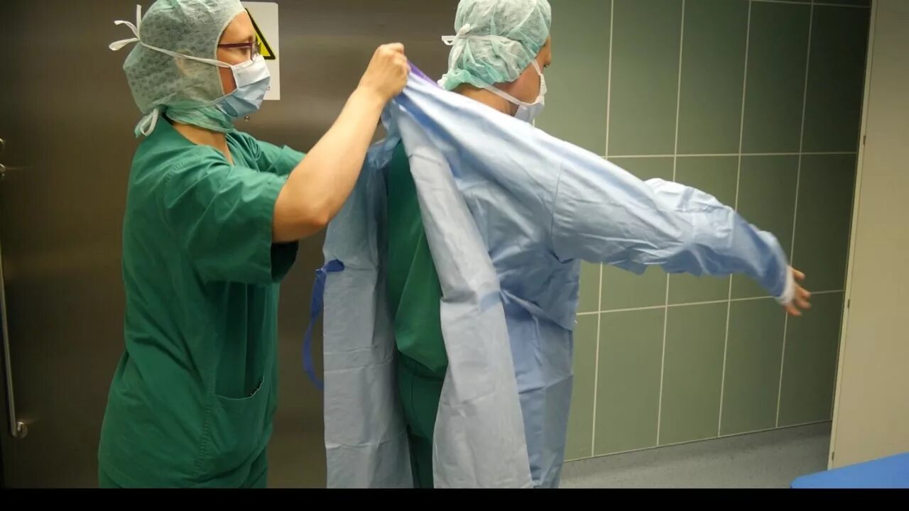 Одевание хирурга. Одевание стерильного халата. Одевание хирурга перед операцией. Одевание стерильного халата на хирурга. Подготовка хирурга к операции