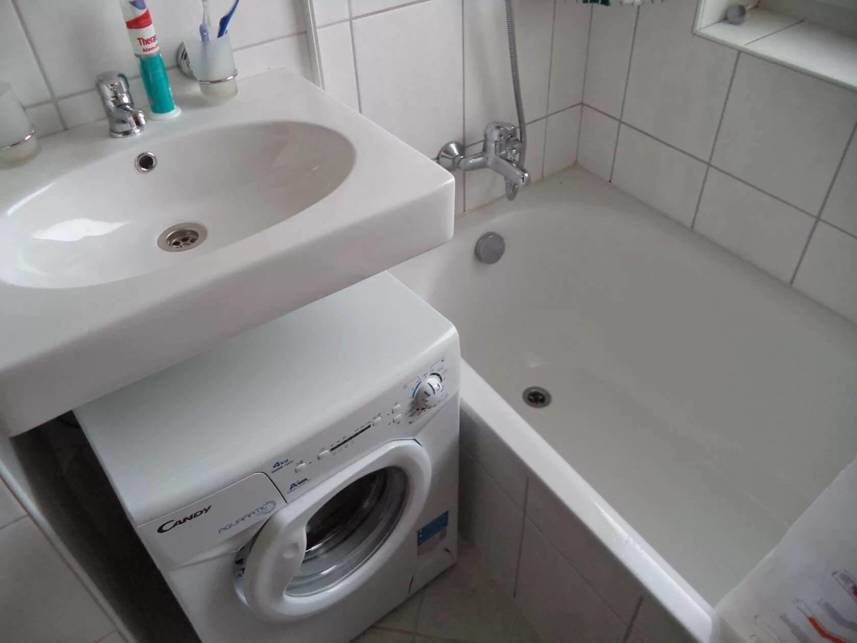 В ванной комнате установлен. Машинка в маленькой ванной. Стиральная машинка под раковиной. Маленькая ванная стиралка под раковиной. Раковина и стиральная машина в маленькой ванной.