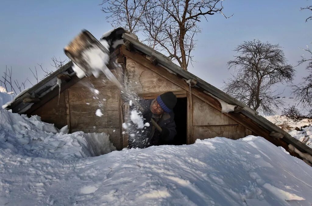 Снег с крыши на дорогу. Занесенная снегом избушка. Деревня в снегу. Снег по крышу. Дом занесло снегом.