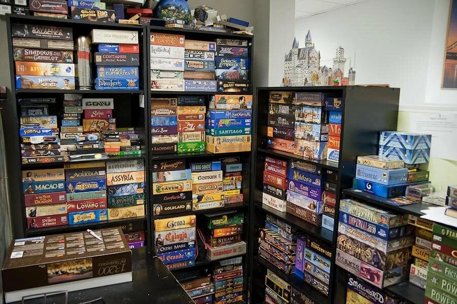 коллекция настольных игр. настольные игры коробки. книжные полки. коллекция настольных игр. много настольных игр.
