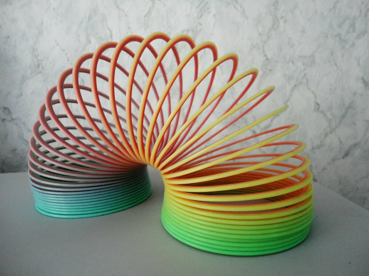 Кто изобрел шагающую пружинку. Ричард джеймс пружинка. Слинки история. Пружина разноцветная. Слинки пружинка 90е.