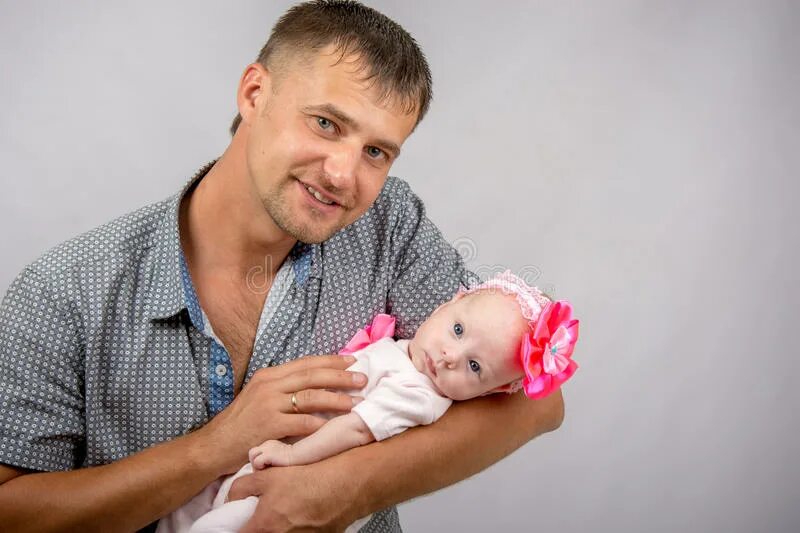 Человек держит ребенка. Мужчина держит в руках новорожденную дочку. Счастливый отец держит новорожденного. Мужчина в костюме держит новорожденного.