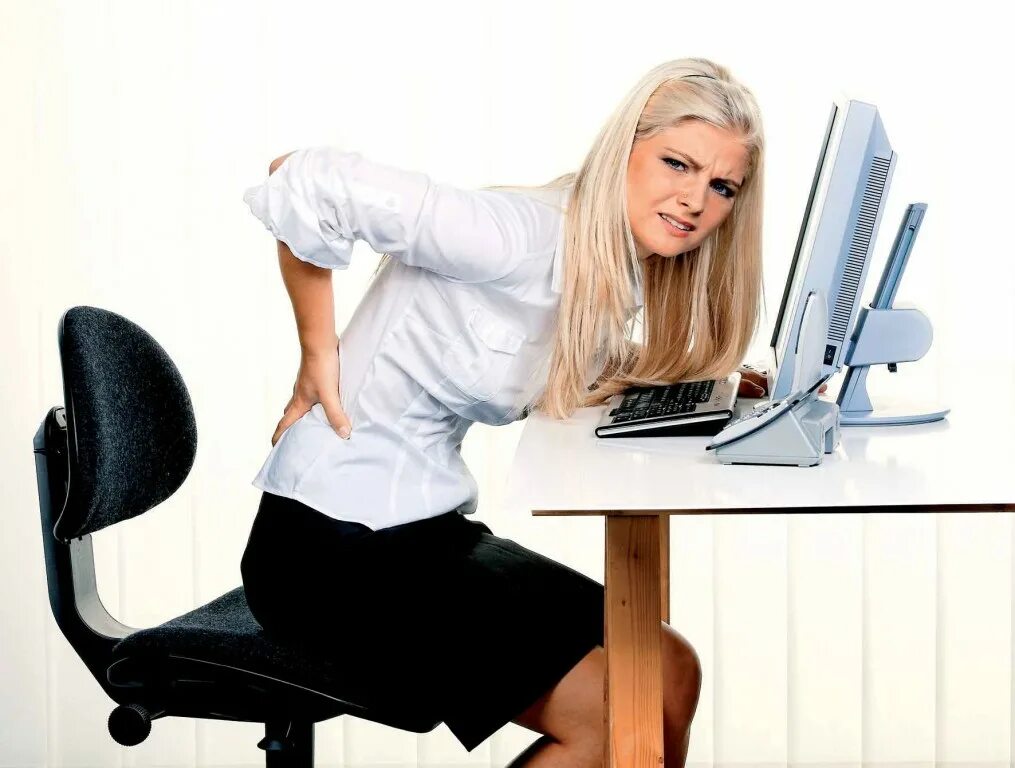 офисный работник. за компьютером со спины. женщина сидит в офисе. у них сидячая работа. офисная боль.