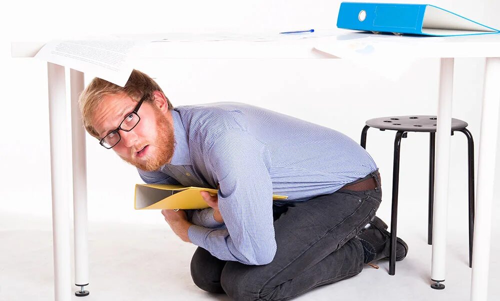 Сидеть под столом. Под столом в офисе. Парень под столом. Человек под столом. Человек под столом.