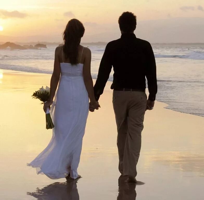 Счастливые влюбленные. Мужчина и женщина на берегу. Мужчина и женщина со спины. Пара идет по берегу моря. С супругом по месту его