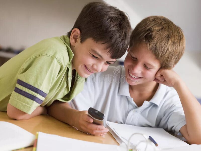 They doing their homework. Два мальчика с телефоном. Школьники спорят о играх. Мальчики рассказали друг другу об уроке. Ребята дружно делают уроки.
