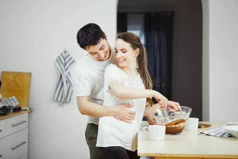 Мужчина обнимает жену на кухне. Муж обнимает жену за столом. Измена мужу кухни
