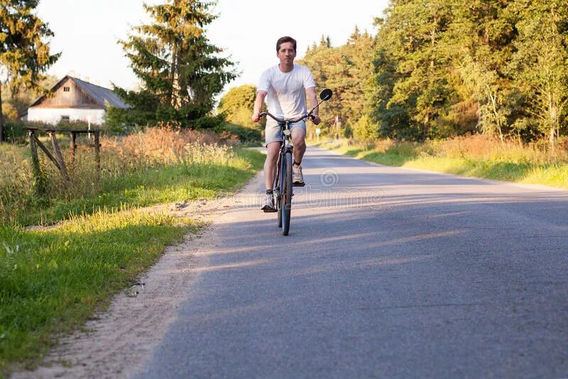 На велосипеде Сельская дорога. Велосипедист едет вперед. Велосипедист на сельской дороге. Велосипед едет по сельской дороге.