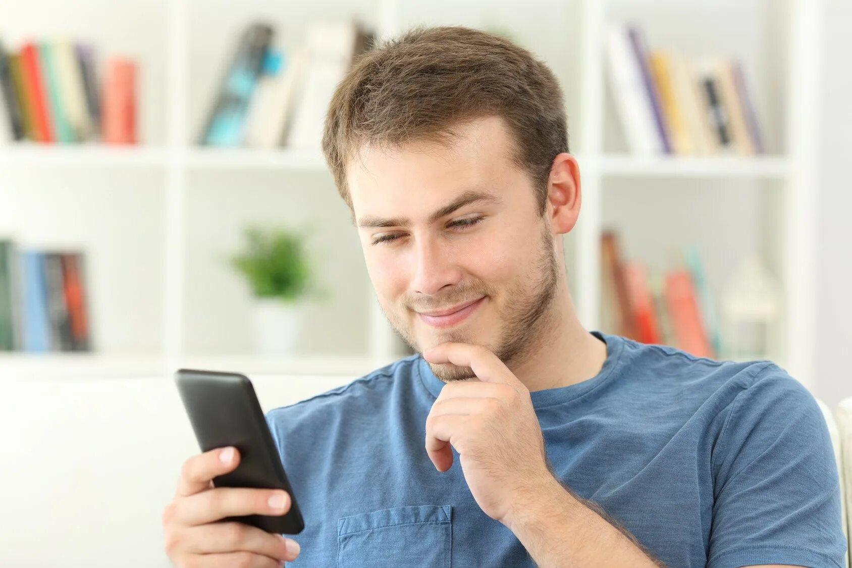 Парень смотрит в телефон. Человек с телефоном в руке. Парень со смартфоном. Мужчина с мобильником. Парень смотрит в телефон.