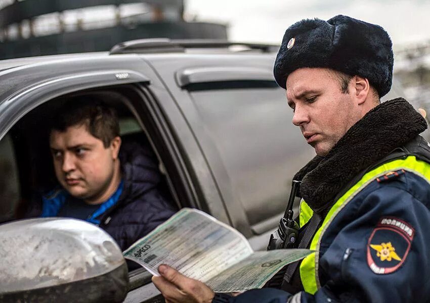 Водитель машины остановиться. Сотрудник ГИБДД проверяет документы. Гаишник и водитель. ДПС проверка документов. Полицейский водитель.