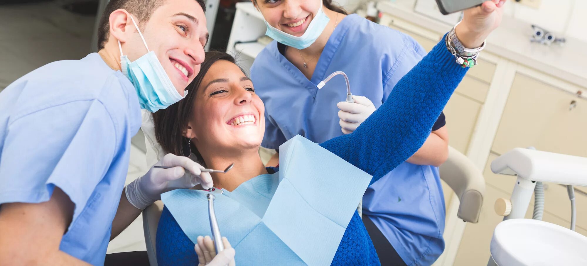 Три стоматолога. Счастливый пациент стоматолога. Прием врача стоматолога. Стоматолог и пациент улыбаются. Общение со стоматологом.