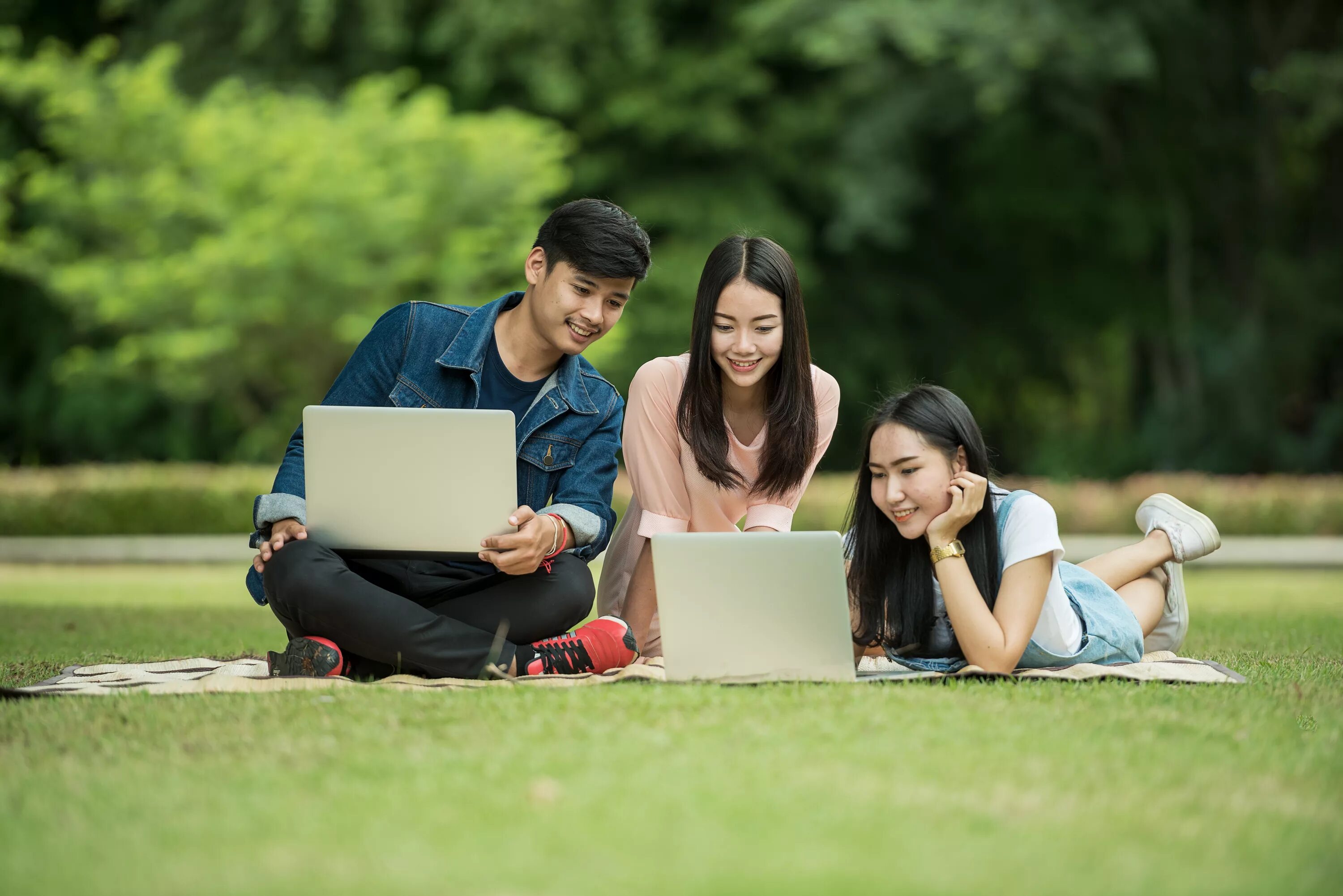 Студенты азиаты. Человек с ноутбуком в парке. Студенты в парке. Учеба на природе. Современный студент.