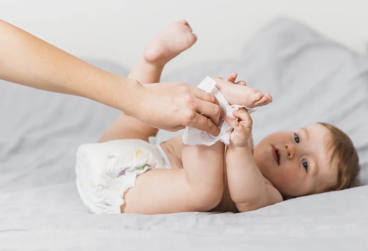 Младенец трет. Младенец в памперсе. baby wipes. ребенок младенец с салфеткой. малыш в подгузнике.