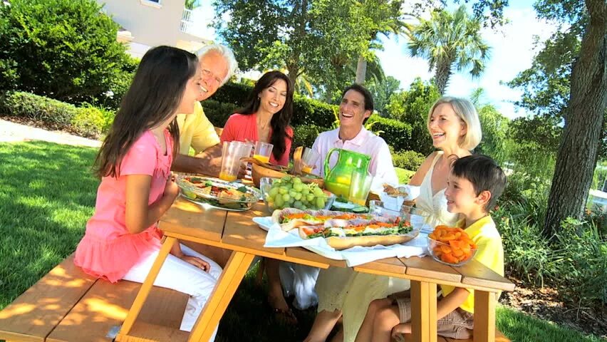 Пикник много людей. Радостные друзья за столом на природе. Go lunch outdoors. Have lunch outdoors. Outdoor gatherings.