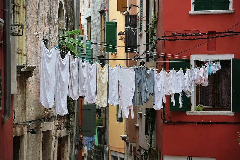 бабушка развешивает белье на улице. белье на веревке. белье сушится на балконе. знамя победы вывешивается на окнах. большие трусы на балконе.
