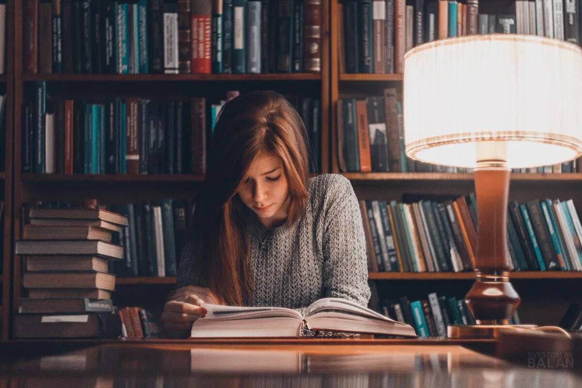 Чтение книг. Чтение в библиотеке. Девушка читает книгу