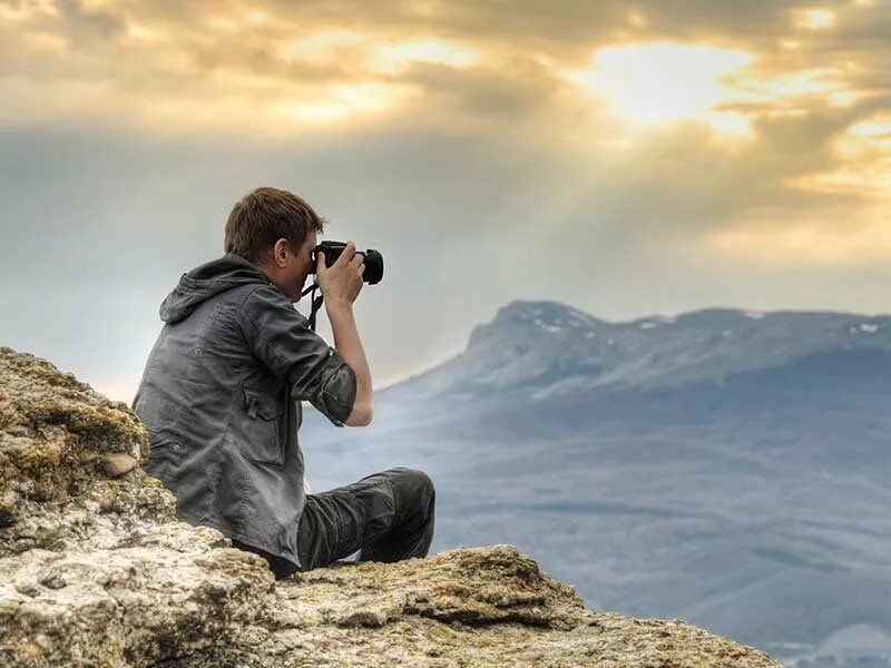 Take a good living. Человек с фотоаппаратом. Парень с фотоаппаратом. Человек в горах. Турист с фотоаппаратом.