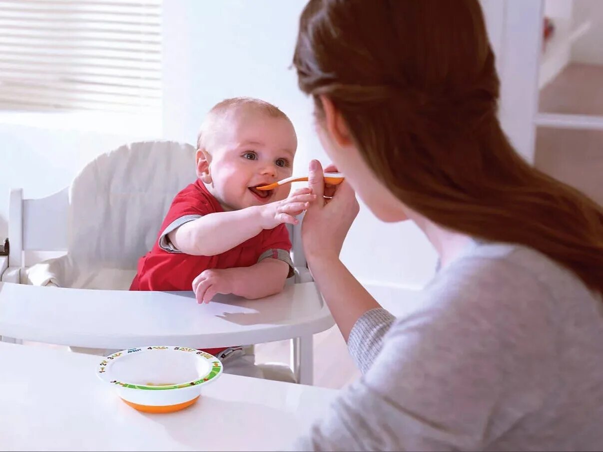 Кормить. Кормление ребенка с ложечки. Детское питание. Мама кормит ребенка. Кормить.