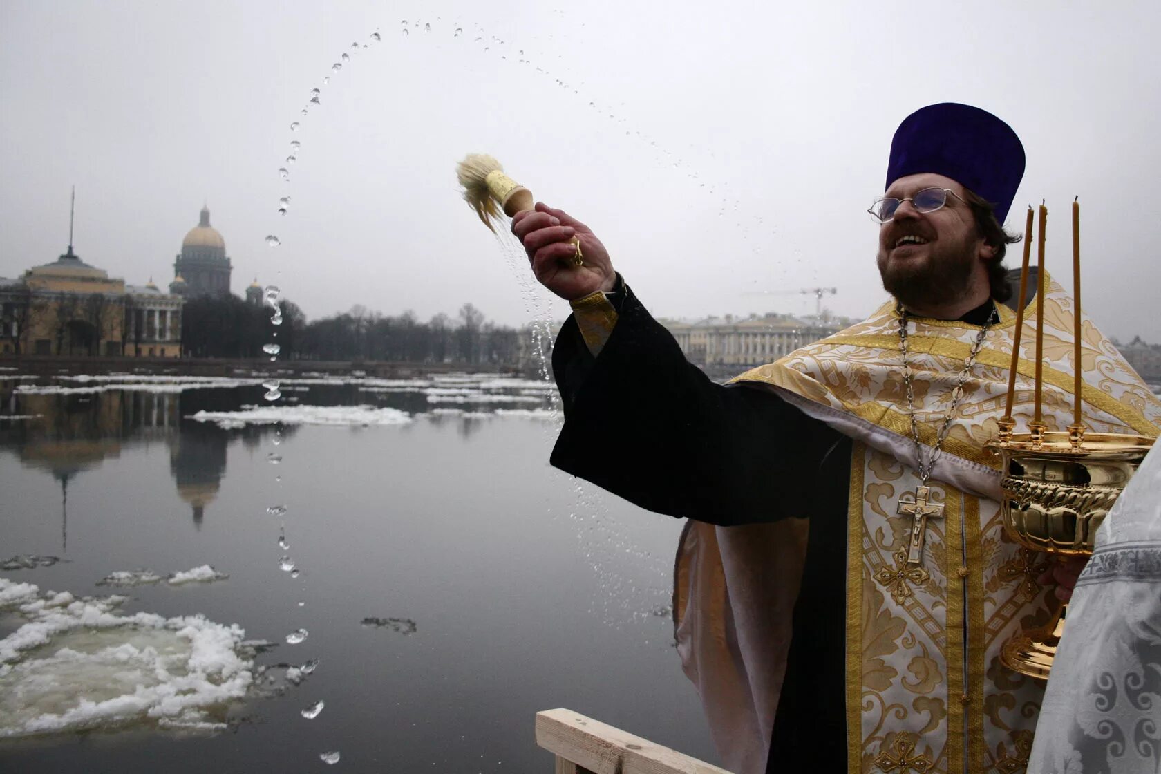 Брызгают святой водой. Священник крещение.