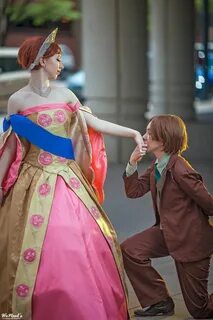 a man kneeling down next to a woman in a pink and gold dress on the street 