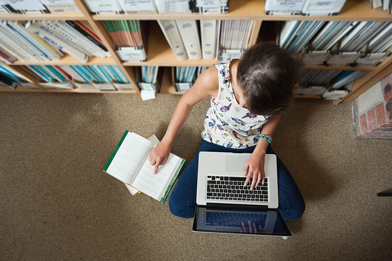 Компьютеры в библиотеке. Ноутбук в библиотеке. Человек с ноутбуком и книгой. Чтение в интернете.