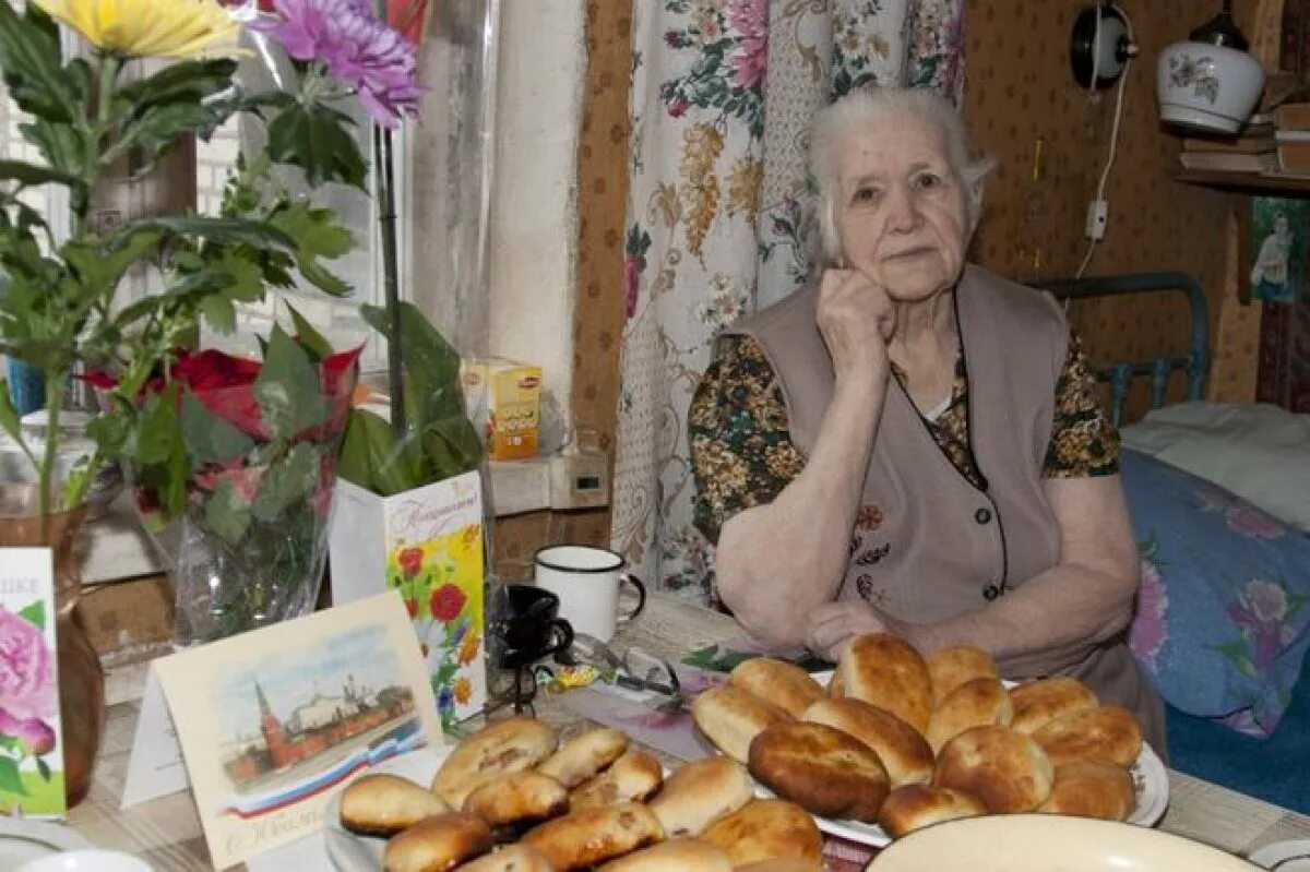 Танечка угости бабушку своим пирогом. Бабулька с пирожками. Бабушка с пирогами. Старушка в деревне за столом. Старушка с пирогами.