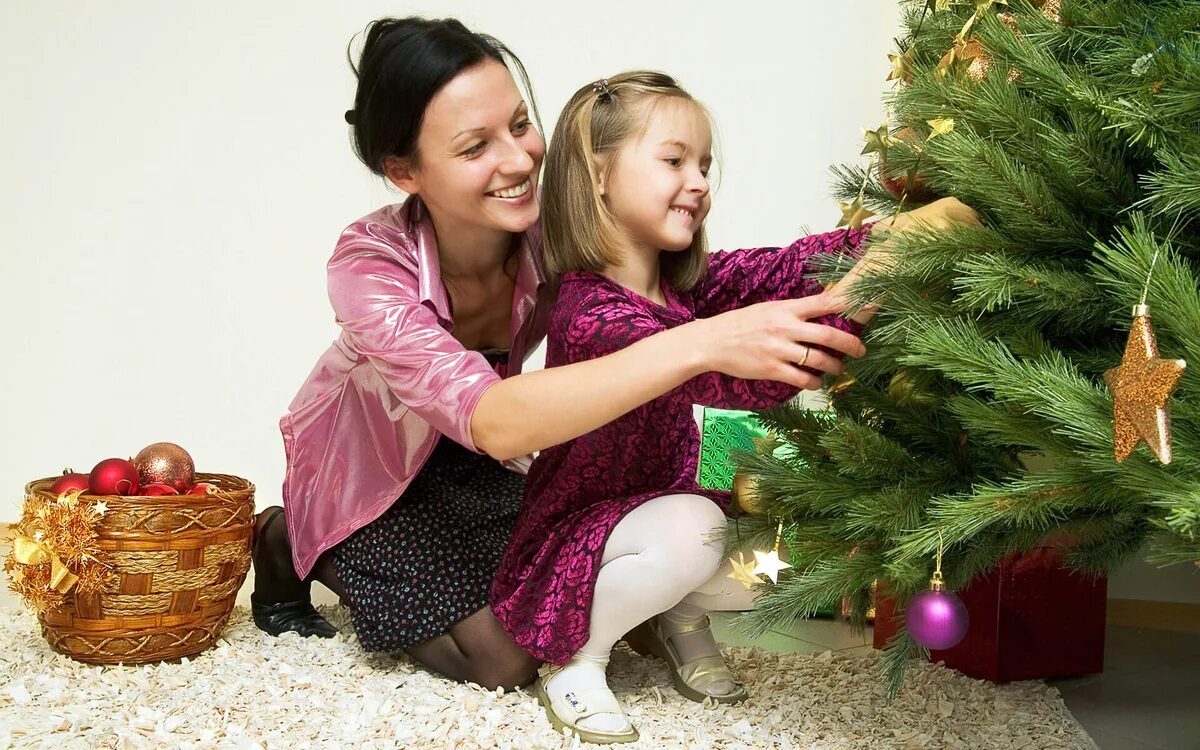 Как привести новый год. Дети наряжают елку. Мама с ребенком наряжают елку. Новый год семья. Елка Новогодняя украшенная дети.