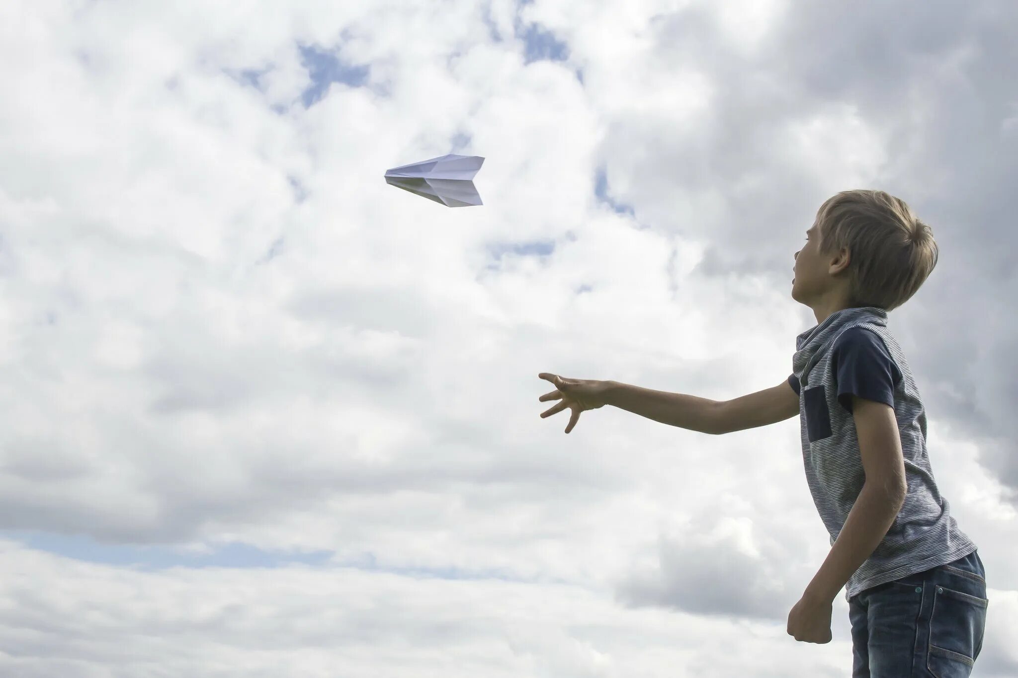 Kid flying. Ребенок с бумажным самолетиком. Запускает бумажный самолетик. Мальчик запускает самолетик. Дети летают.