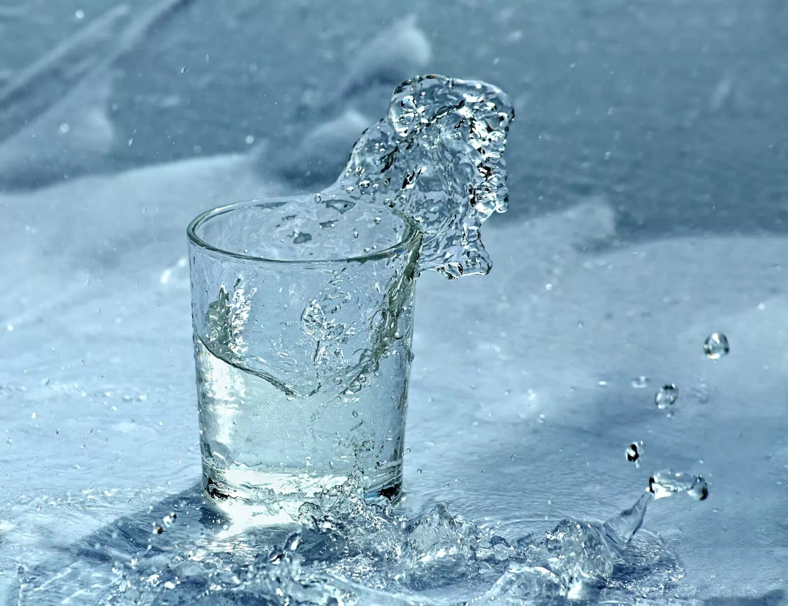 Замерзание воды. Снег и лед в стакане. Стакан со снегом и водой. Стакан воды на фоне снега. Стакан воды зимой.
