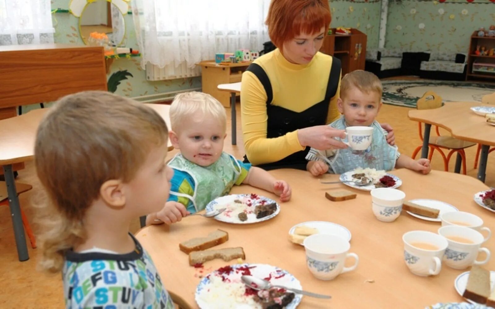 Младший воспитатель в садике. Дети кушают в детском саду. Детский сад ясли. Воспитатель младшей группы. Обед в детском саду в младшей группе.