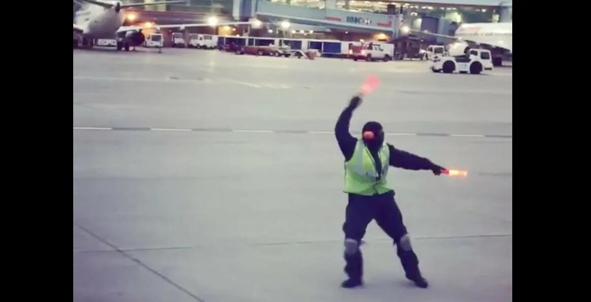 Регулировщик в аэропорту. Регулировщик на взлетной полосе. регулировщик в аэропорту танцует. регулировщик самолетов на посадке. человек с флажками на взлетной полосе.