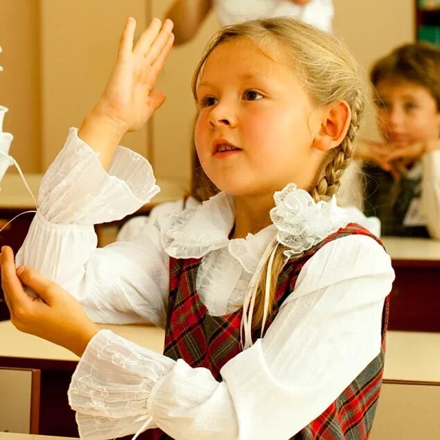 Ученица. Прилежная ученица. Девочка в школе на уроке. Школьник тянет руку.