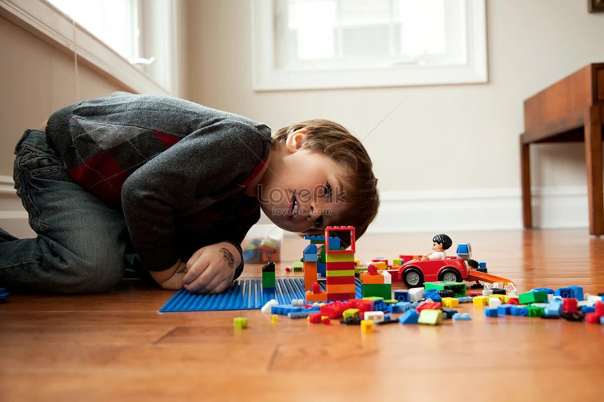 Мальчик играет на полу. Ребенок собирает конструктор.