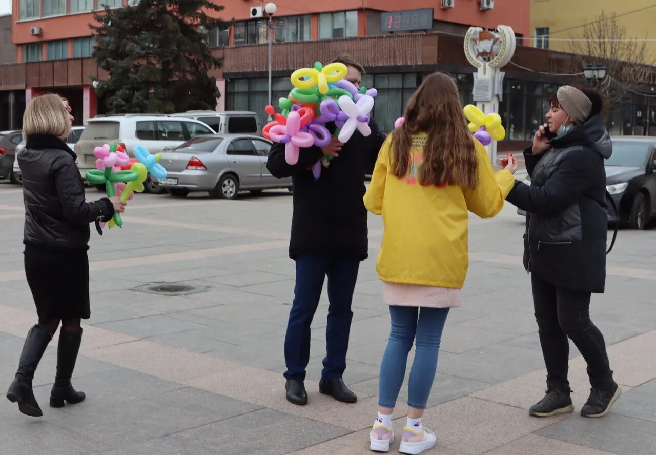 Волонтеры цветы. Вручение цветов женщинам. Дарит ей цветы.