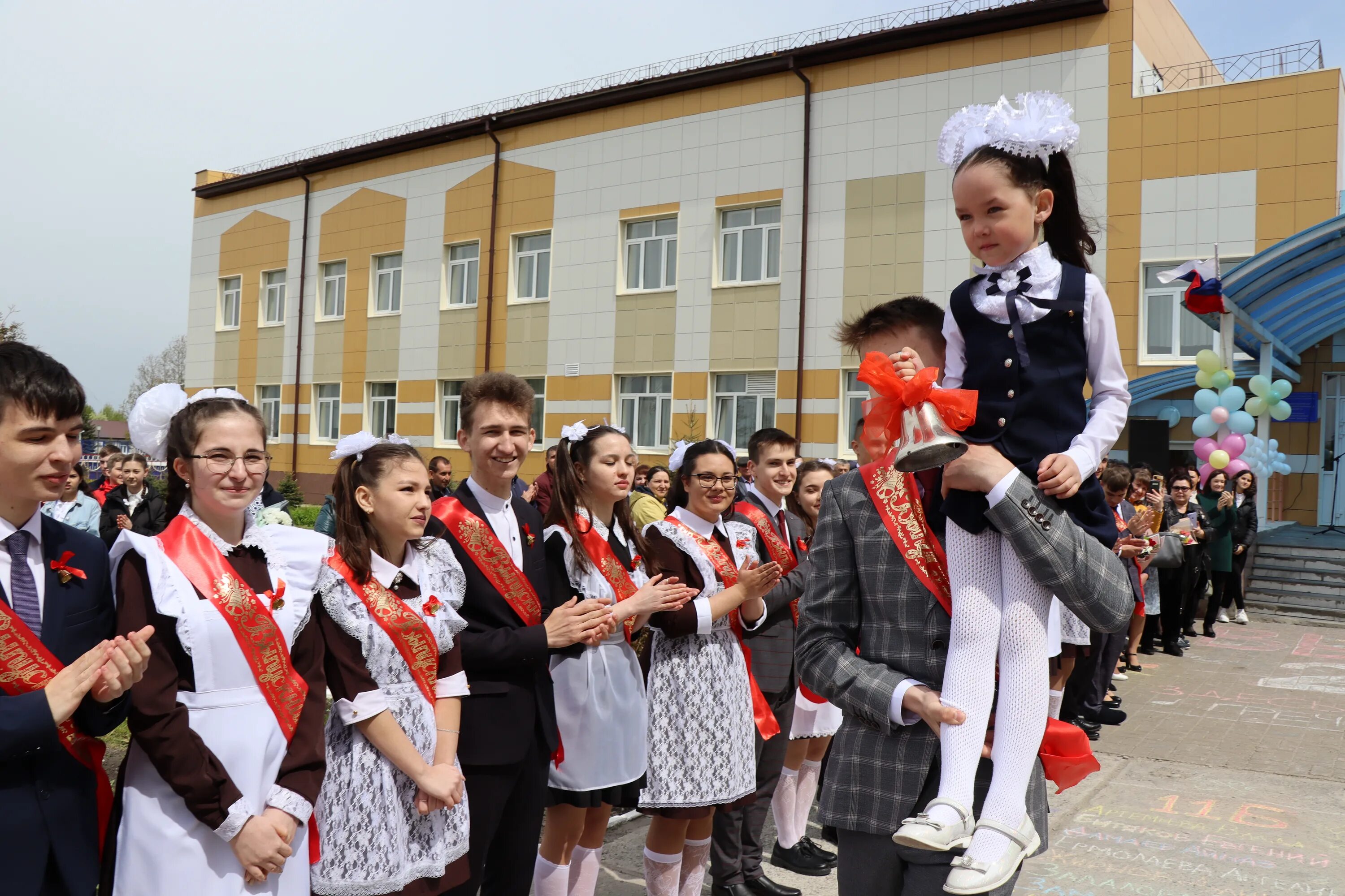 Последний звонок первоклассница на плече. Первоклашки на последнем звонке. Выпускник несет первоклассницу последний звонок. Последний звонок СОШ 1 2013 Г Дрожжаное.