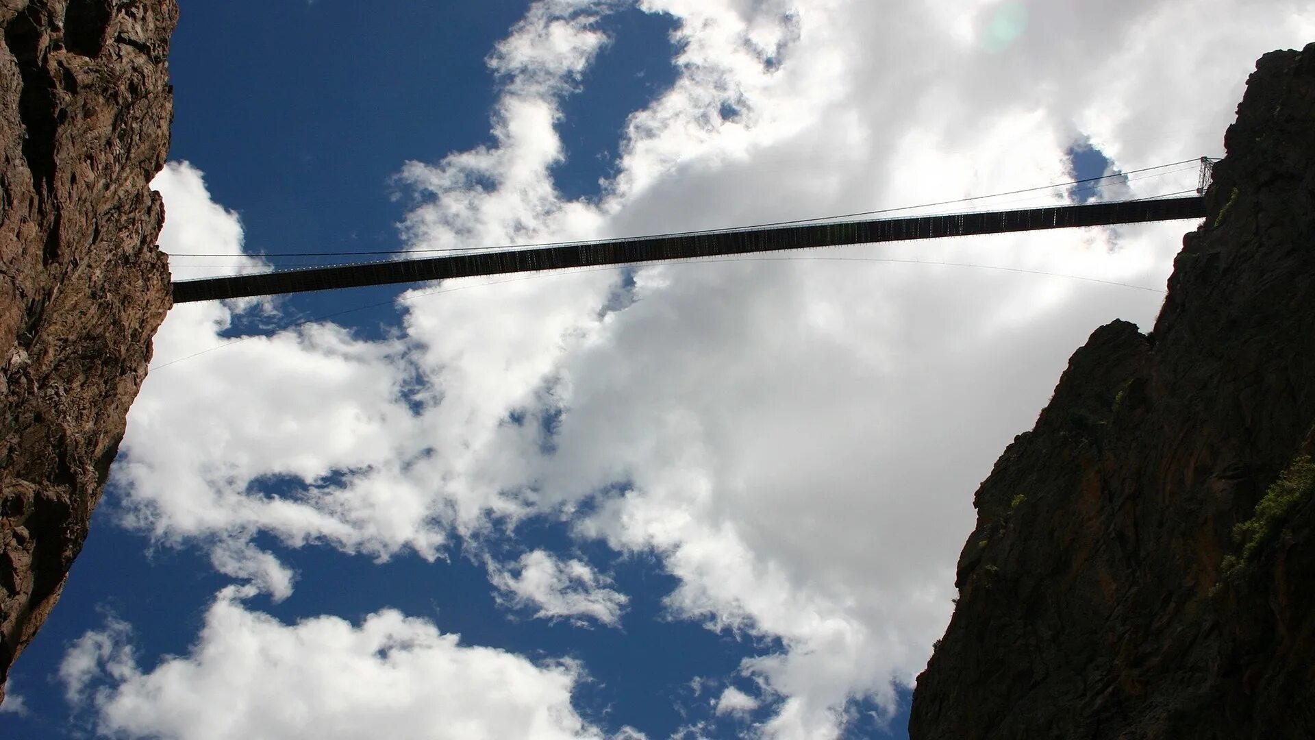 Скалолаз альпинист. Альпинисты в горах. Навесная переправа. Канат над пропастью. Виа феррата стальной трос.