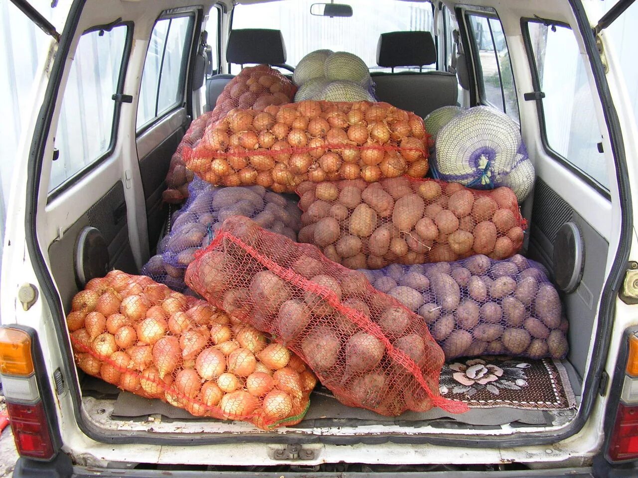 Груженная мешками. Транспортировка овощей и фруктов. Перевозка картошки. Машина для перевозки картошки. Овощи в багажнике автомобиля.