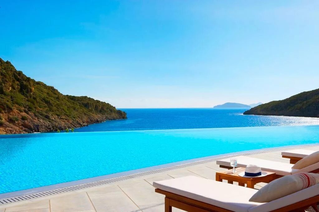 Отель с бассейном с видом на море. Daios Cove Luxury Resort Villas. Крит - Daios Cove Luxury Resort & Villas Blue Palace Resort & Spa. Бассейн с видом на море. Столик с видом на море.