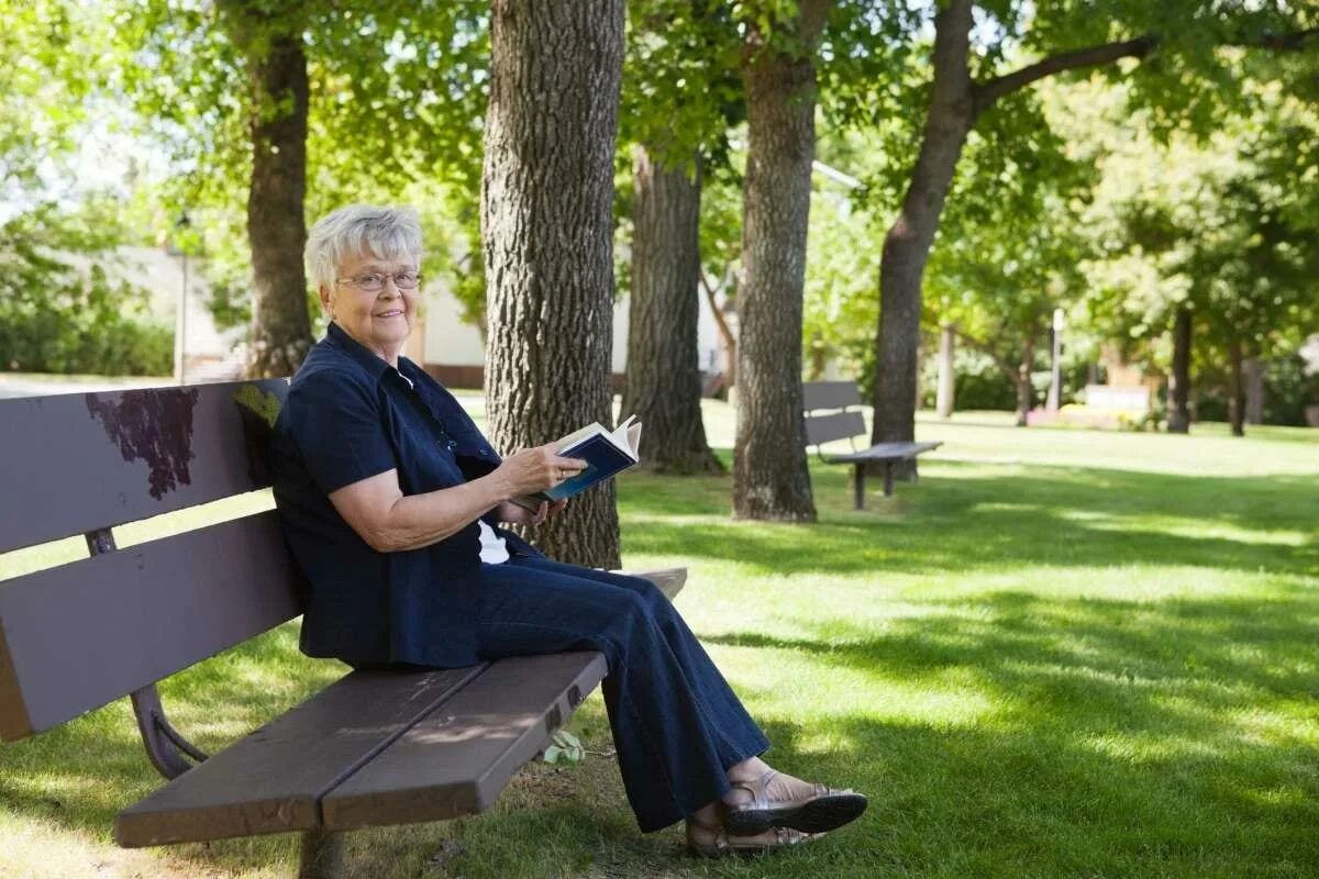Пожилая женщина на лавочке. Пожилая женщина на скамейке. Пожилая женщина в парке. Чтение на скамейке.