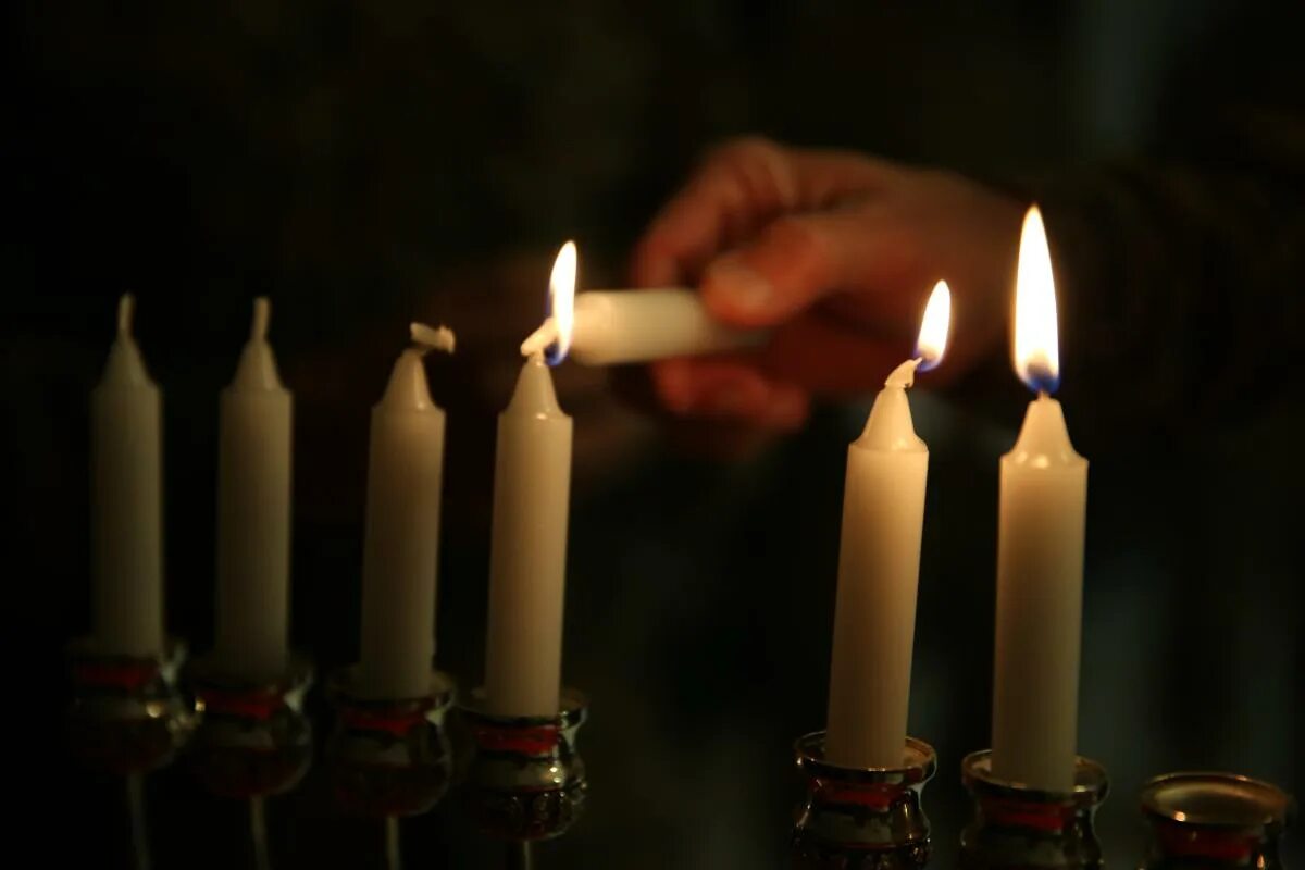 огонь от свечи. спичка зажигает свечу. свечка в руках в темноте. свечки надо зажигать. горение свечи.