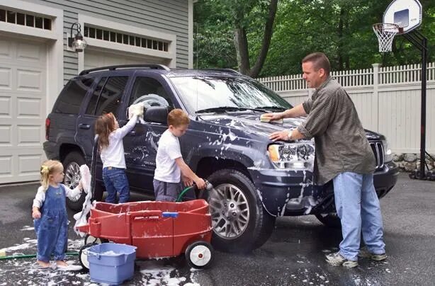The car is being washed. Family car wash. they wash the car. andy wash the family car. a picture of a family washing a car.
