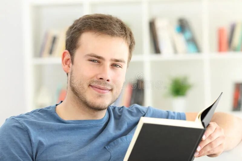 Он смотрит в книгу. Человек с книгой смотрит в камеру. мужчина читающий книгу в профиль. человек смотрит в книгу. мужчина на фабрике читает книгу фото для презентации.