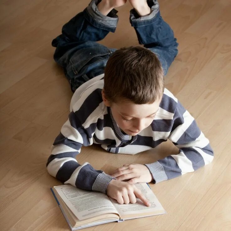 Мальчик лежит на полу. Мальчик лежит с книгой. Мальчик читает книгу. Ребенок читает на полу.