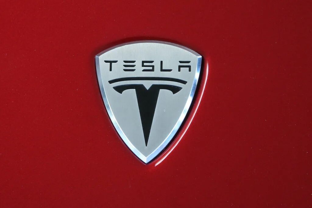 Знак теслы на машине. Электромобиль Тесла логотип. Тесла знак на машине. Tesla марка. Значок марки автомобиля Тесла.