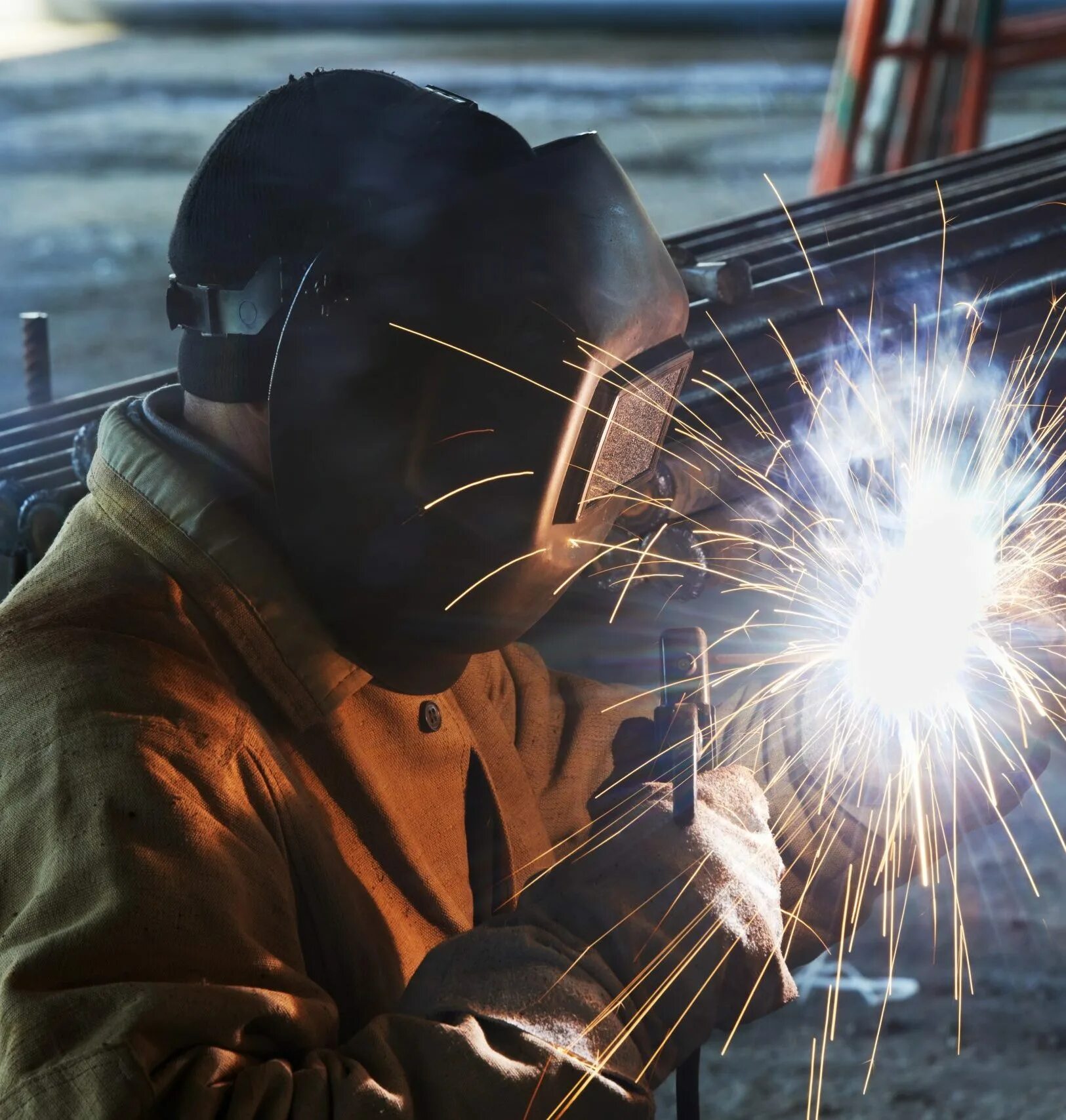 Сварщик ручной дуговой сварки плавящимся покрытым электродом. Сварщик. Фотография сварщика в работе. Ручная сварка. Сварщик фон.