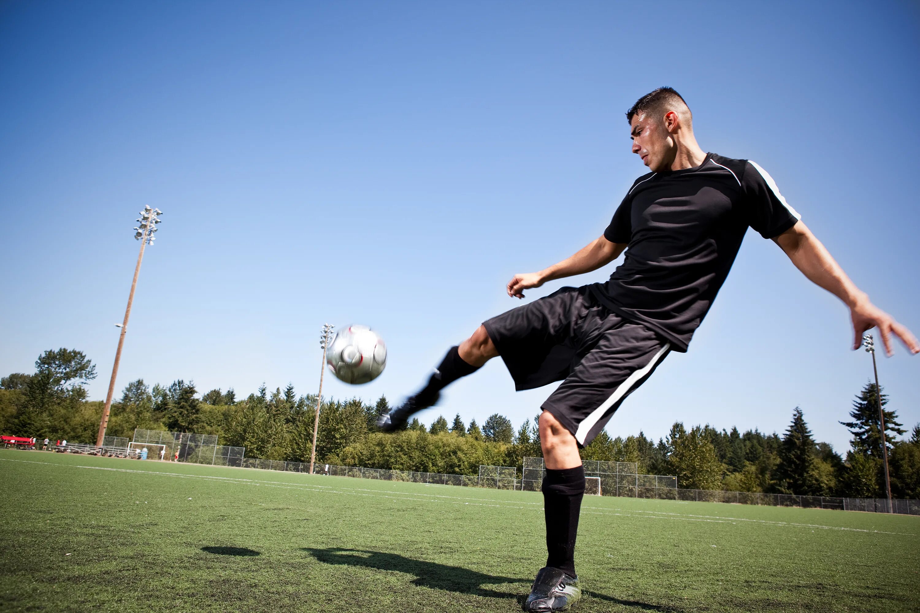 Мужчина играет в футбол. Футболист с мячом. Парень с мячом. Футболист пинает мяч. Человек с футбольным мячом.