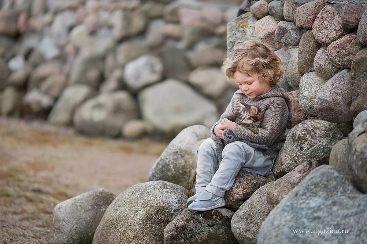 Мальчик чидит на Каменек. Ребенок сидит на Камне. Камень для детей. Мальчик сидит на Камне.