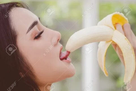 Asian woman is eating and licking the yellow banana for sensuality and temp...