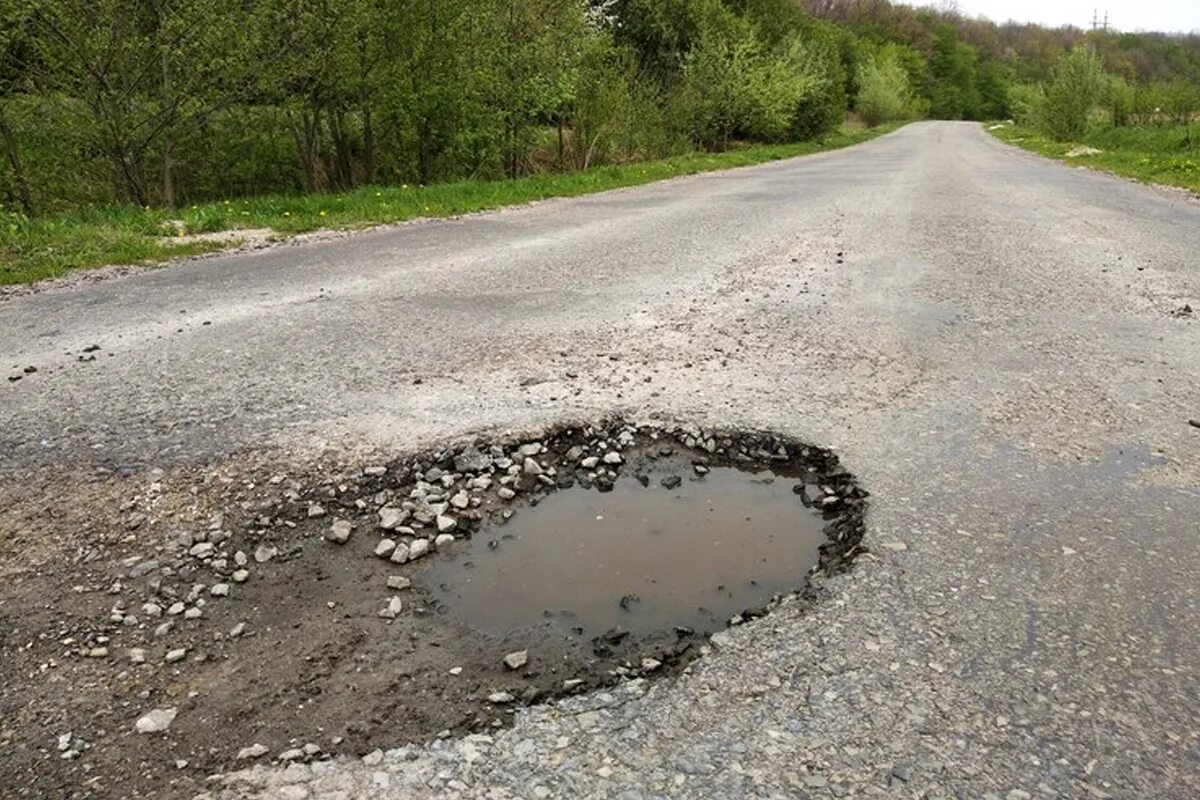 Вода на дороге. Трещины на дороге. Яма на автотрассе. Стоящая вода на дороге.